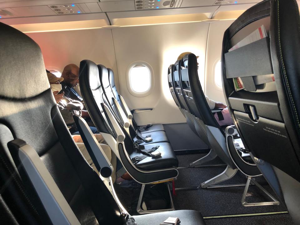 An empty row of seats with seatbelts visible on a Spirit Airlines flight.