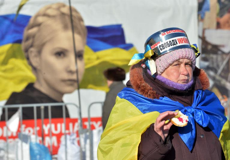 An opposition activist eats a sandwich on Independence Square in Kiev on January 30, 2014, in front of a picture of jailed ex-premier Yulia Tymoshenko