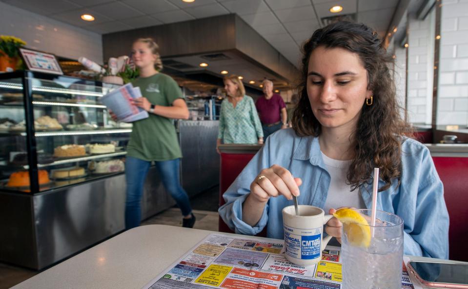 York Daily Record reporter Lena Tzivekis stirs her coffee, before chatting with her server Kyra Taylor, at Round the Clock Diner in Manchester Township.