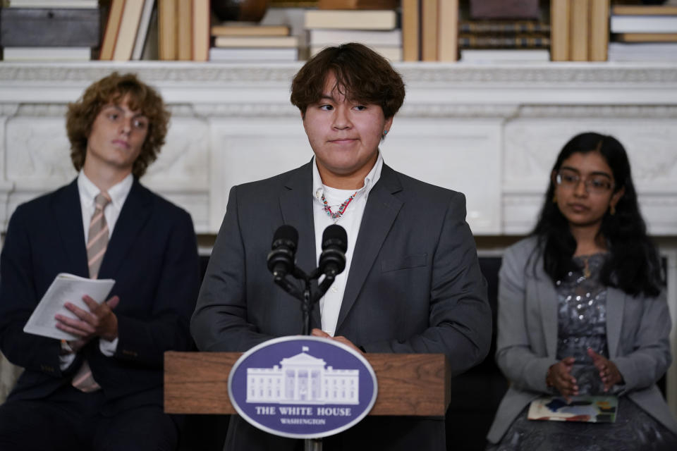 Jesse Begay from Santa Fe, N.M., pauses for applause after reading his poem during event for the Class of 2022 National Student Poets hosted by first lady Jill Biden at the White House in Washington Tuesday, Sept. 27, 2022. Seated behind from left, Winslow Hastie, Jr., from Charleston, S.C., and Vidhatrie Keetha, from the Bronx borough of New York. (AP Photo/Carolyn Kaster)