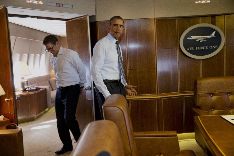 President Barack Obama enters a conference room past White House press secretary Jay Carney to sign an executive order streamlining the export/import process for American business, Wednesday, Feb. 19, 2014, during a flight aboard Air Force One en route to Toluca, Mexico. In Mexico, the president is expected to participate in the seventh trilateral North American Leaders Summit Meeting. (AP Photo/Jacquelyn Martin)