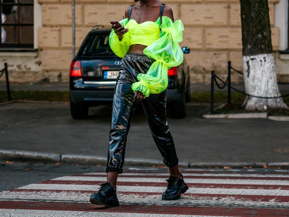 person walking down a street wearing a neon yellow shirt and plant leather pants