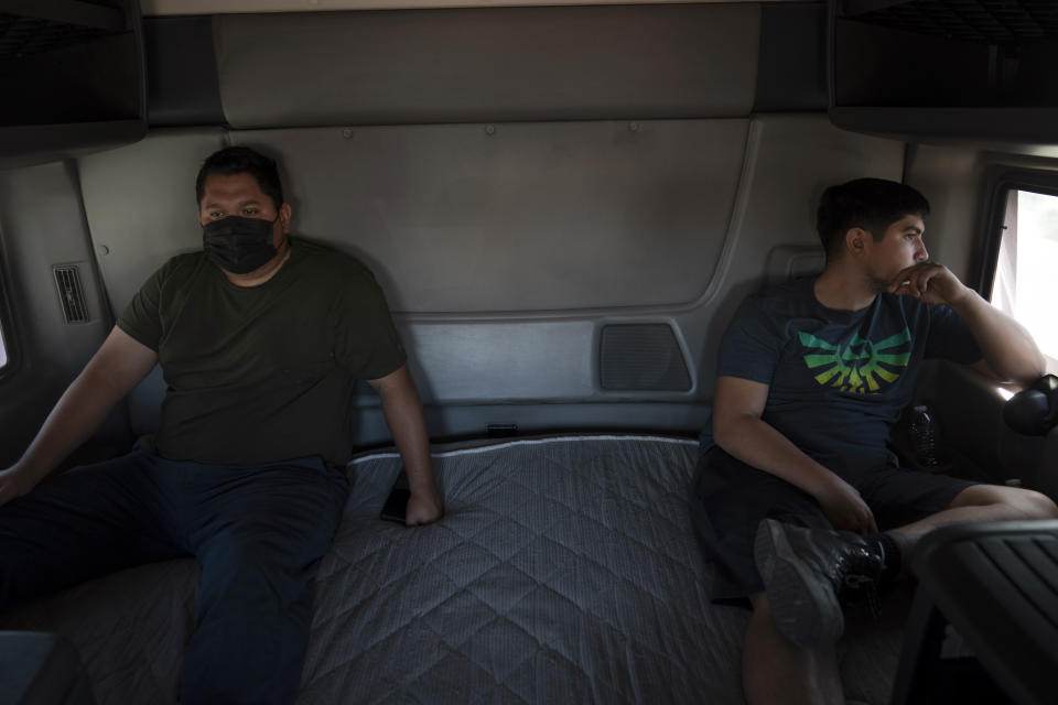 Two student drivers Edgar Lopez, right, and Jose Garcia sit in a sleeper cab of a practice truck as their classmate drives the vehicle along the street in Inglewood, Calif., Monday, Nov. 15, 2021. Amid a shortage of commercial truck drivers across the U.S., a Southern California truck driving school sees an unprecedented increase in enrollment numbers. The increase is big enough that the school is starting an evening class to meet the demand, according to Tina Singh, owner and academy director of California Truck Driving Academy. "I think that's only going to continue because there's a lot of job opportunities. We have over 100 active jobs on our job board right now," said Singh. The companies that normally would not hire drivers straight out of school are "100 percent" willing to hire them due to shortage issues, the director added. (AP Photo/Jae C. Hong)