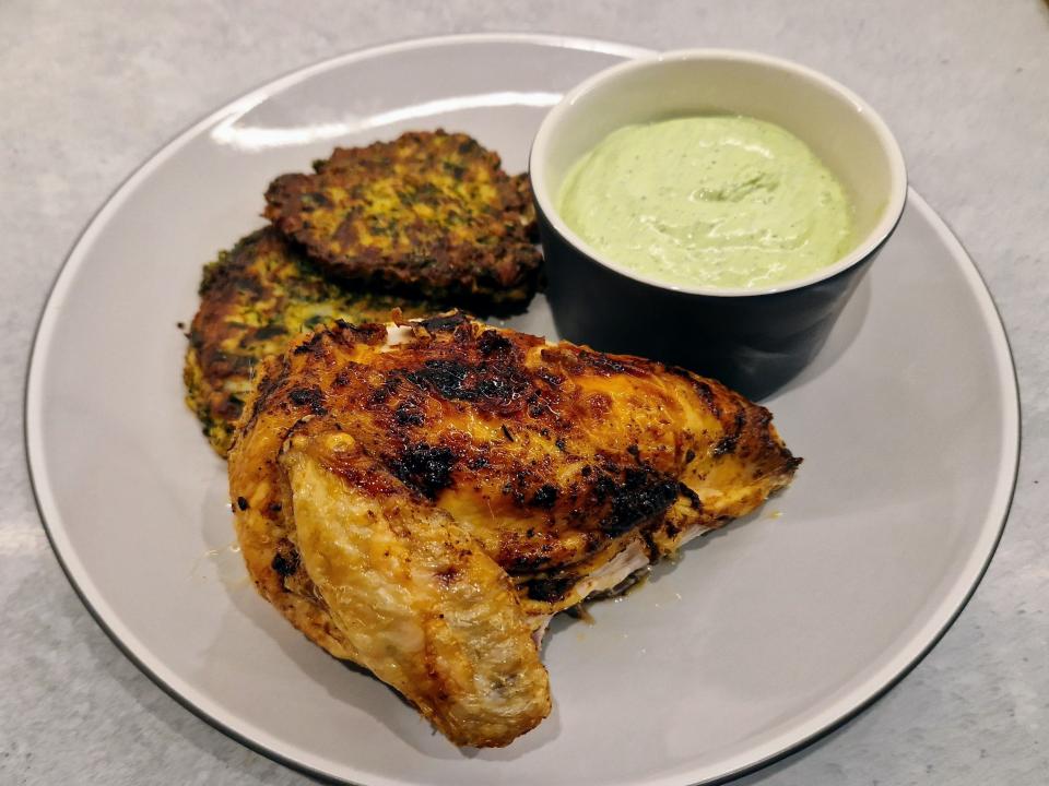 roasted chicken, cauliflower latkes, and a creamy sauce on a plate