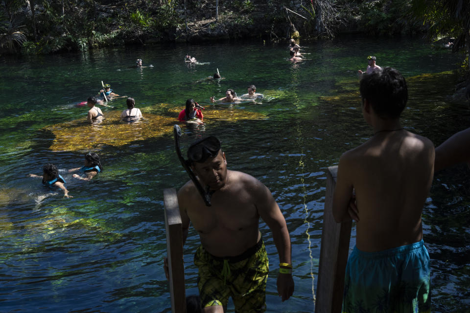 Tourists wade in the waters of the cenote "Jardin del Eden," or Eden's Garden, near Tulum, Mexico, Wednesday, Feb. 28, 2024. These glowing sinkhole lakes, known as cenotes, are a part of one of Mexico's natural wonders: A fragile system of thousands of subterranean caverns, rivers, and lakes that wind beneath Mexico's southern Yucatan peninsula. (AP Photo/Rodrigo Abd)