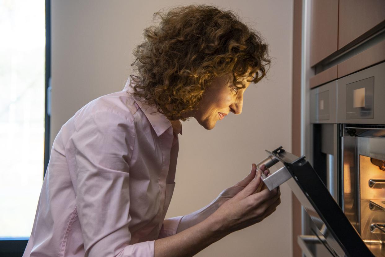 woman checking on food in oven