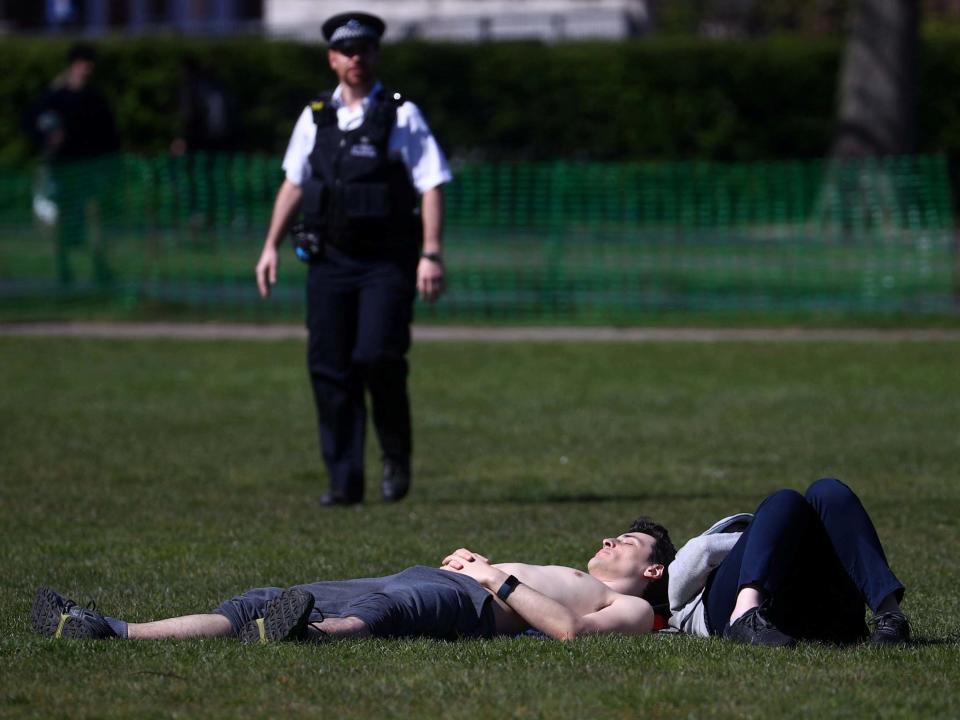 A police officer approaches a sunbather in Greenwich Park, south London: REUTERS