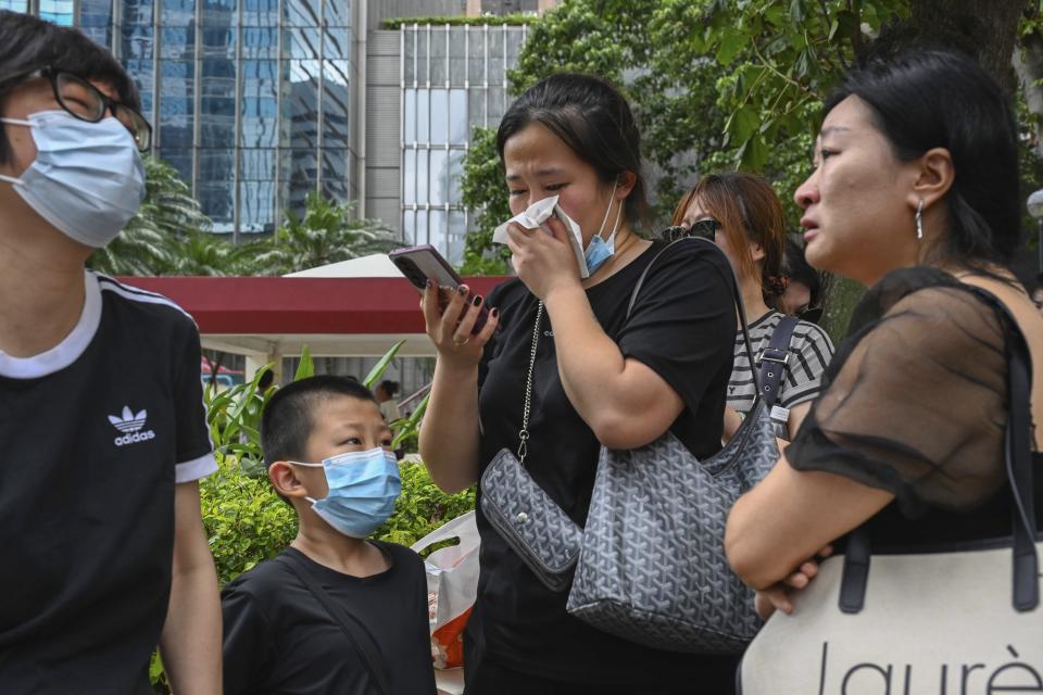 People react during a funeral for Coco Lee outside a funeral home in Hong Kong, Tuesday, Aug. 1, 2023. Lee was being mourned by family and friends at a private ceremony Tuesday a day after fans paid their respects at a public memorial for the Hong Kong-born entertainer who had international success. (AP Photo/Billy H.C. Kwok)