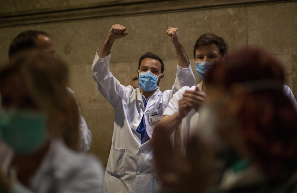 Health workers react as people applaud from their houses in support of the medical staff that are working on the COVID-19 virus outbreak at the main gate of the Hospital Clinic in Barcelona, Spain, Thursday, March 26, 2020. The new coronavirus causes mild or moderate symptoms for most people, but for some, especially older adults and people with existing health problems, it can cause more severe illness or death. (AP Photo/Emilio Morenatti)