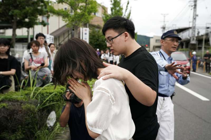 京都動畫公司18日陷入火海，釀成33死35傷的慘劇，民眾在火場附近放置鮮花悼念死難者。（美聯社）