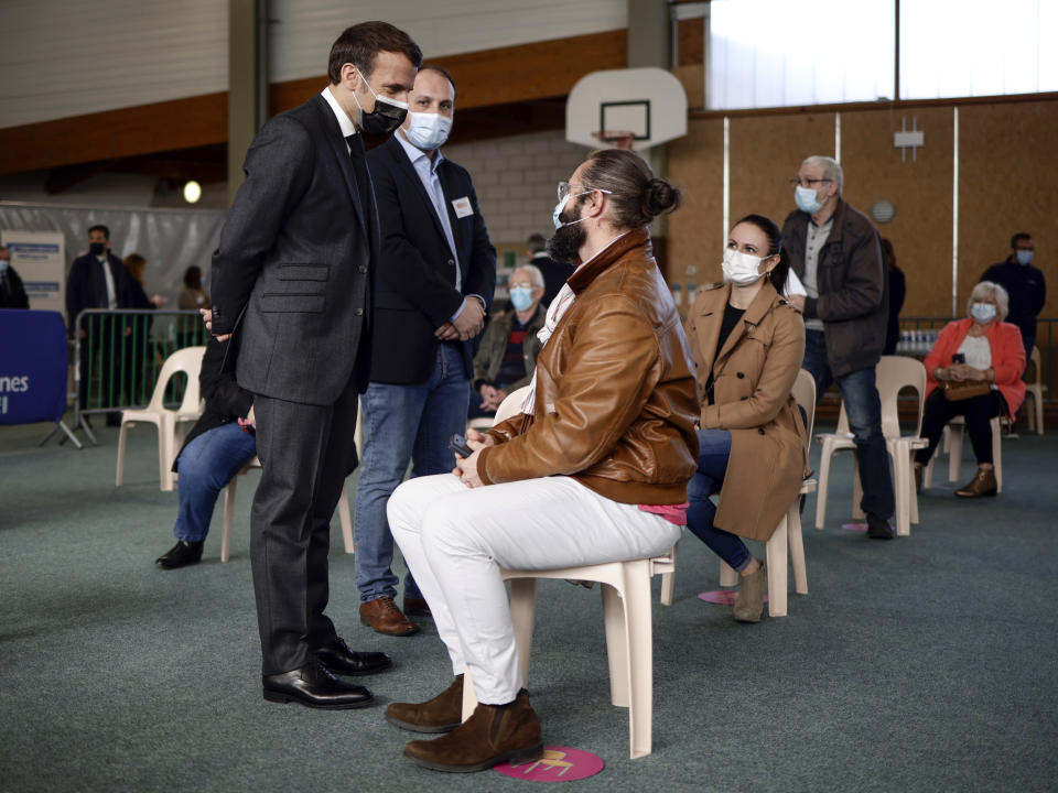 French President Emmanuel Macron talks to a man after he received a Pfizer COVID-19 vaccine at the vaccination center of Valenciennes, northern France, Tuesday, March 23, 2021. The French government has backed off from ordering a tough lockdown for Paris and several other regions despite an increasingly alarming situation at hospitals with a rise in the number of COVID-19 patients. (Yoan Valat/Pool Photo via AP)