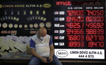 A man sits outside an exchange office in Istanbul, Friday, Aug. 7, 2020. Turkey's currency tumbled further Friday, hitting another record low. The Turkish lira dropped to 7.3677 against the dollar before making a recovery. The lira is down about 19% versus the U.S. currency since the beginning of the year. (AP Photo/Emrah Gurel)