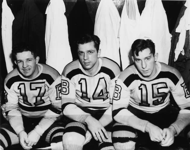 Canadian professional hockey players and childhood friends (left to right) Bobby Bauer (1915 - 1964), Woody Dumart (1916 - 2001), and Milt Schmidt of the Boston Bruins' legendary 'Kraut Line' sit on a bench in the locker room and pose for a photograph before their last professional game before joining the Royal Canadian Air Force, 1942. (Photo by Bruce Bennett Studios/Getty Images)