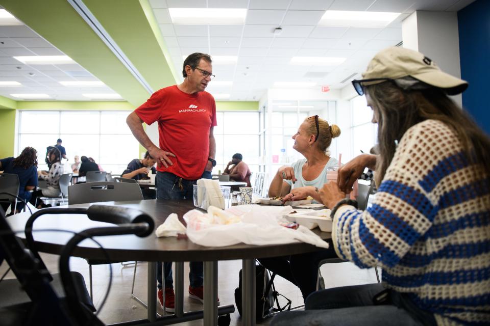 Manna Church pastor Wayne Tate, left to right, talks with Tammi Chavis and Megan Vincent as they eat lunch at the Day Resource Center on Wednesday, May 15, 2024. Manna Dream Center will be the new operator of the Day Resource Center starting July 1.