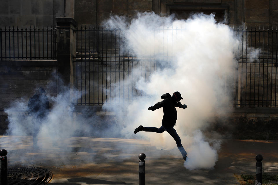 FILE - In this April 19, 2018 file photo an activist kicks a tear canister gas shot by riot police during a protest in support of the French railway employees, in Paris, France. Thousands of people are expected to march in protest at French President Emmanuel Macron's reforms as rail strikes and student protests continue to shake the country. (AP Photo/Francois Mori, File)