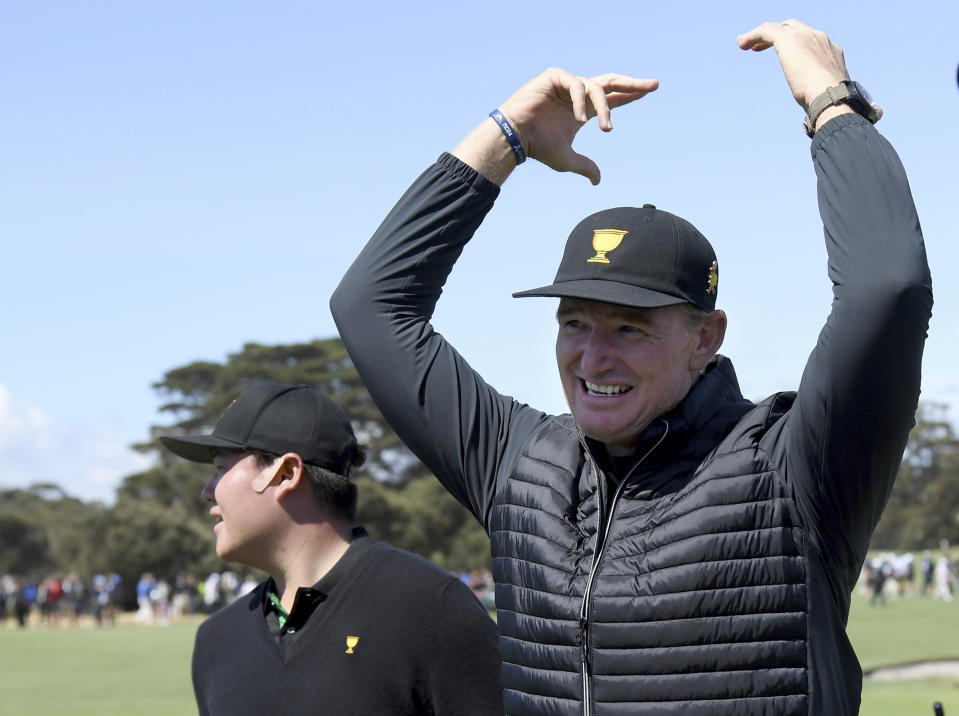 International team captain Ernie Els, right, waves to the crowd after the International team take a 4-1 lead after the opening round of the President's Cup golf tournament at the Royal Melbourne Golf Club in Melbourne, Thursday, Dec. 12, 2019. (AP Photo/Andy Brownbill)