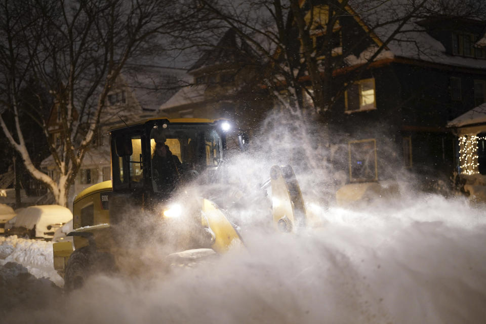 A city worker in a wheel loader clears snow on Norwood Avenue as crews work through the night to reopen the city after a deadly blizzard over the weekend, Monday, Dec. 26, 2022. (Derek Gee/The Buffalo News via AP)