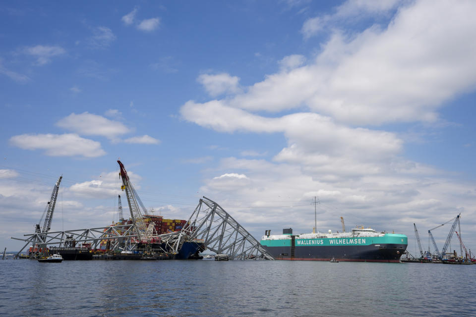 A vessel, center right, moves past the stranded container ship Dali, through a newly opened deep-water channel in Baltimore after being stuck in the harbor since the Francis Scott Key Bridge collapsed four weeks ago, Thursday, April 25, 2024. (AP Photo/Matt Rourke)