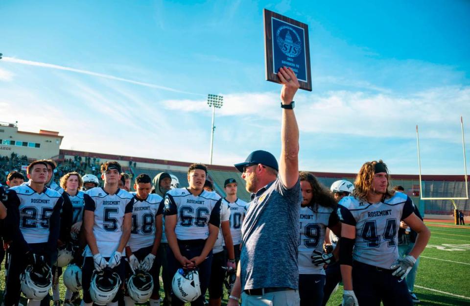 Rosemont coach Rick Wanlin shows the CIF Sac-Joaquin Section Division VI finalist plaque to the crowd while congratulating his team on its season after coming up short against the Argonaut Mustangs in the championship game on Saturday at Hughes Stadium in Sacramento. At right stands Walin’s son Adam (44), a senior tight end and linebacker for the Wolverines.