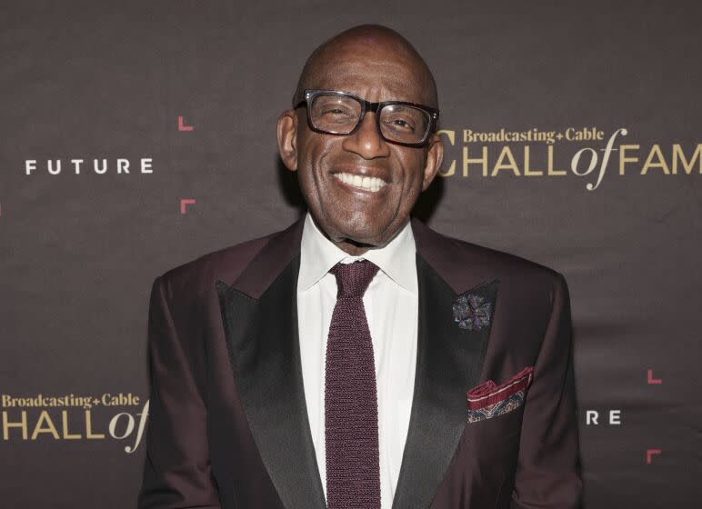 Al Roker in eyeglasses and a dark suit smiles broadly against a promotional backdrop