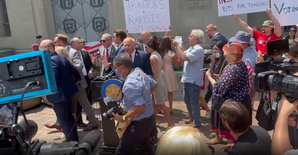 Reps Marjorie Taylor Greene, Matt Gaetz, Louie Gohmert and others are ushered away by security as protesters crowded and shouted down the group during a press conference outside of the Justice Department (Twitter: Zachary Petrizzo)