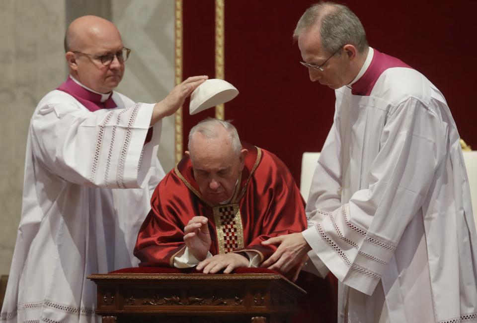 Pope Francis gets his skull cap adjusted as he celebrates Mass for the Passion of Christ in St. Peter's Basilica, at the Vatican, Friday, April 19, 2019. Pope Francis began the Good Friday service at the Vatican with the Passion of Christ Mass and hours later will go to the ancient Colosseum in Rome for the traditional Way of the Cross procession. (AP Photo/Alessandra Tarantino)