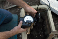 FILE - Cason Gilmer, a senior field customer service representative from the Las Virgenes Municipal Water District, installs an advanced water metering system in Agoura Hills, Calif., Jan. 5, 2022. The sight of fountains, swimming pools, gardens and golf courses in Western cities like Phoenix, Los Angeles, Las Vegas, San Diego and Albuquerque can seem jarring with drought and climate change tightening their grip on the region. But Western water experts say they aren’t necessarily cause for concern. Many Western cities over the past three decades have diversified their water sources, boosted local supplies, and use water more efficiently now than in the past. (AP Photo/Jae C. Hong, File)