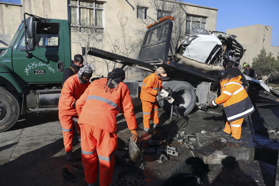 Afghan security personnel and municipality workers remove a damaged vehicle after a roadside bomb attack in Kabul, Afghanistan, Tuesday, Dec. 22, 2020. A roadside bomb tore through a vehicle in the Afghan capital of Kabul Tuesday, killing multiple people, police said. (AP Photo/Rahmat Gul)