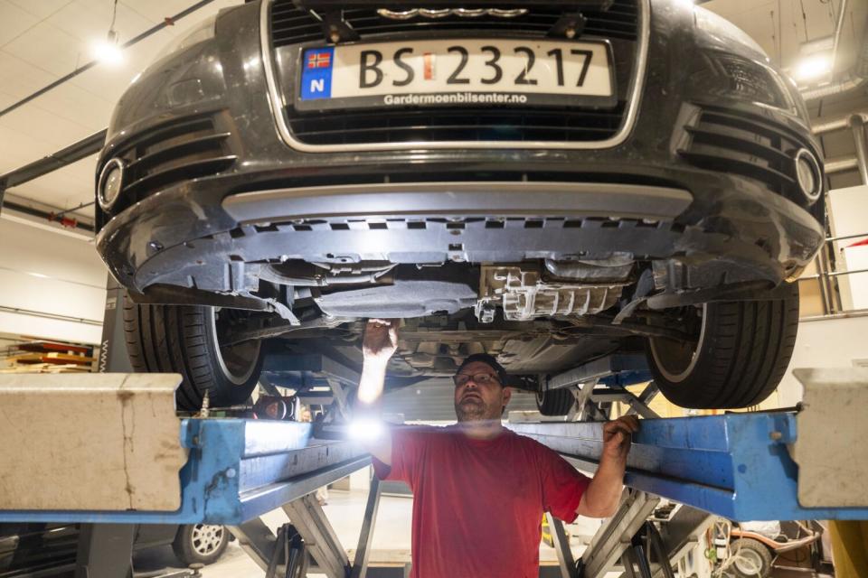 An inmate works under a car