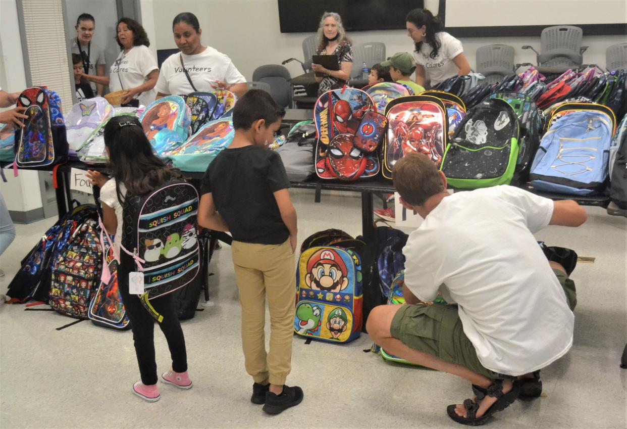 Volunteers help kids select new backpacks filled with school supplies for their grade level at Mujeres de Colonias' annual distribution event Tuesday at the city of Fort Collins Streets Department operations center, 625 Ninth St.