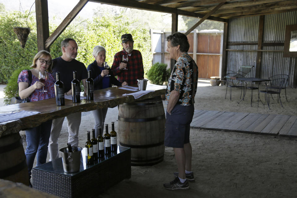 In this Wednesday, Nov. 6, 2019 photo, Mark Dankowski, right, leads a tasting for a group of people visiting the Soda Rock Winery in Healdsburg, Calif. The winery's main building was incinerated in the recent wildfires, but visits and tastings continue at a barn on the winery property. Despite a late October blaze that raged through one of the world's best-known wine-growing regions. forcing evacuations in two mid-sized towns, wine production in Sonoma County escaped largely unscathed. (AP Photo/Eric Risberg)