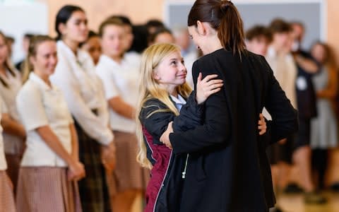 New Zealand Prime Minister Jacinda Ardern receives a hug from a student during her visit to Cashmere High School which lost two students during a mass shooting 