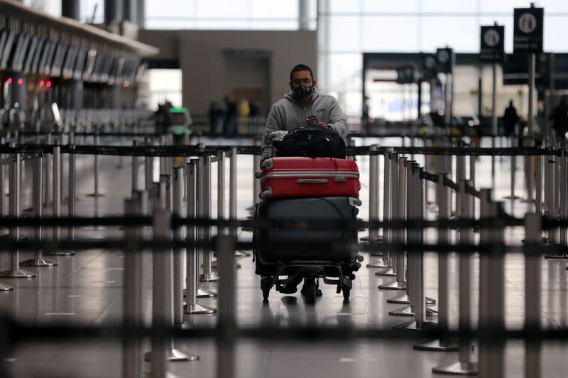 FILE PHOTO: A passenger wearing a protective mask carries his luggage at the El Dorado International Airport, in Bogota