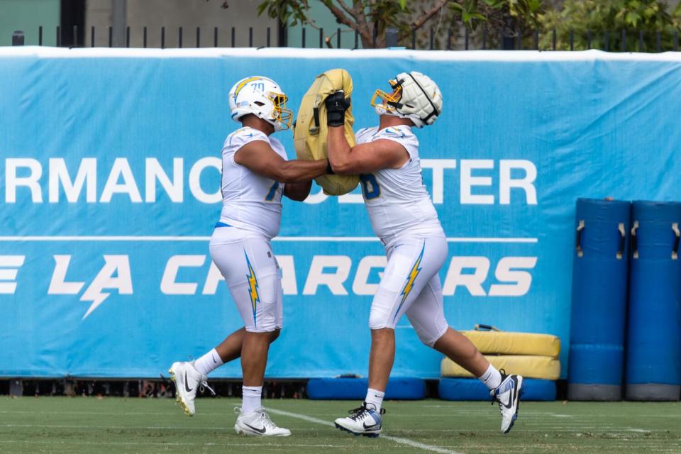 Los tackles ofensivos iniciales de los Chargers, Rashawn Slater (izquierda) y Joe Alt, se combinan en un ejercicio de bloqueo durante la práctica.