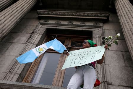 A demonstrator holds a placard reading "We want 105", referring to the two-thirds majority of Congress needed to strip Guatemalan President Otto Perez Molina of his presidential immunity, outside the Congress in Guatemala City, September 1, 2015. REUTERS/Jorge Dan Lopez