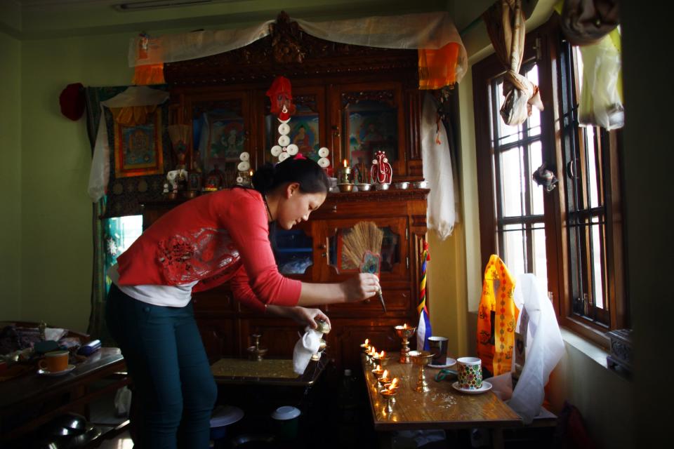 Phinjum Sherpa, 17, daughter of Ang Kaji Sherpa, killed in an avalanche on Mount Everest, lights a butter lamp in front of a portrait of her father in their rented apartment in Katmandu, Nepal, Wednesday, April 23, 2014. Dozens of Sherpa guides packed up their tents and left Mount Everest's base camp Wednesday, after the avalanche deaths of 16 of their colleagues exposed an undercurrent of resentment by Sherpas over their pay, treatment and benefits. (AP Photo/Niranjan Shrestha)