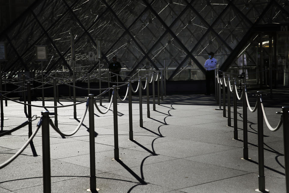 FILE - In this Tuesday, June 23, 2020 file photo, a guard stands in front of the Louvre museum entrance during a visit ahead of its reopening next July 6, in Paris. After “a very bad year,” Paris tour operator Marc Vernhet sees a ray of light with the promised return of tourists from the United States and elsewhere who are welcome in France as of Wednesday, June 9, 2021 if they have been vaccinated against the coronavirus. (AP Photo/Christophe Ena)