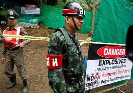 A police officer and soldier stand guard in front of Tham Luang cave complex, where 12 schoolboys and their soccer coach are trapped inside a flooded cave, after Thailand's government instructed members of the media to move out urgently, in the northern province of Chiang Rai, Thailand, July 8, 2018. REUTERS/Soe Zeya Tun