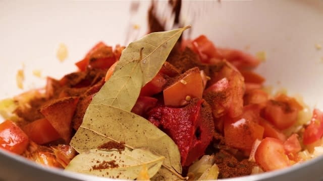 Adding bay leaves, tomato paste, tomatoes, paprika to the pan