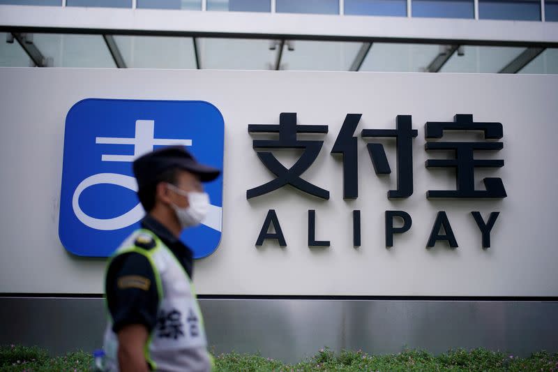 FILE PHOTO: A security guard walks past an Alipay logo at the Shanghai office of Alipay, owned by Ant Group which is an affiliate of Chinese e-commerce giant Alibaba, in Shanghai