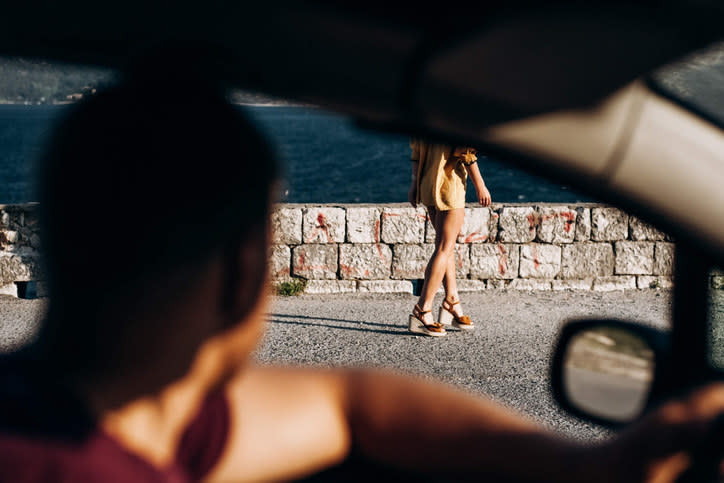 A man catcalling a woman from his car