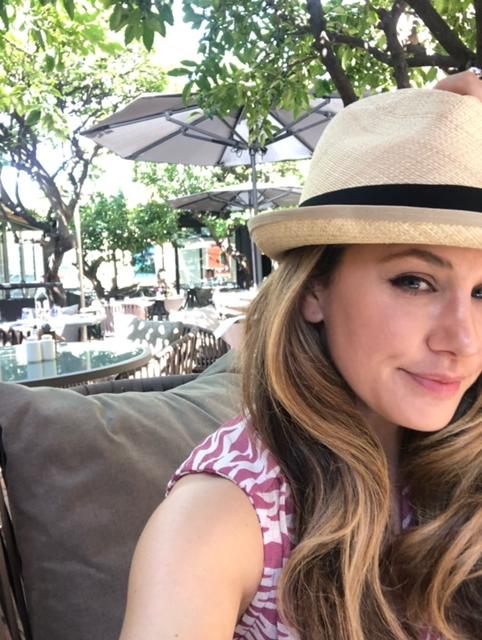 Kirsten Laiken Brown wearing a hat at an outdoor cafe