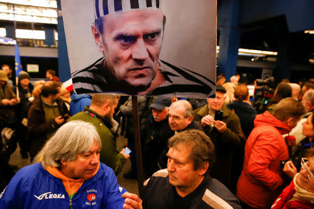 Demonstrators hold a poster depicting European Council President Donald Tusk dressed as a prisoner as they wait for his arrival at the central train station in Warsaw, Poland April 19, 2017. REUTERS/Kacper Pempel