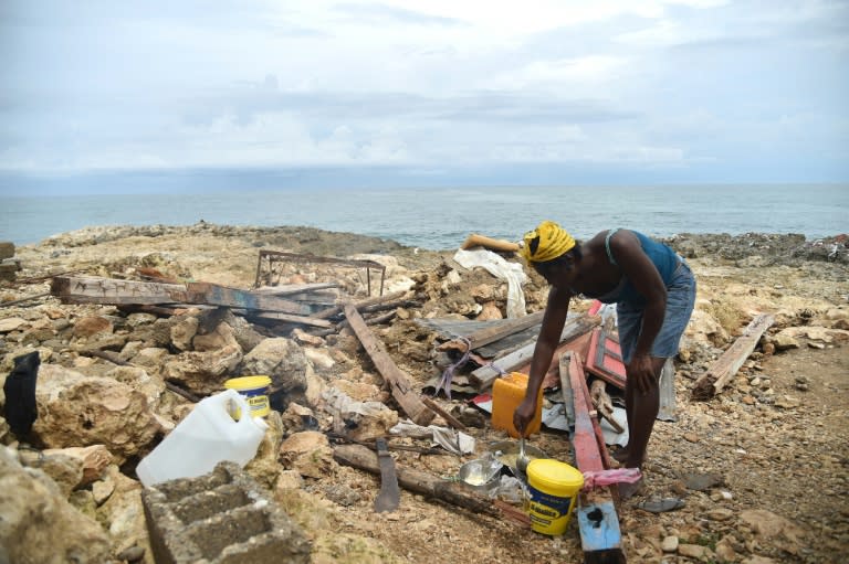 Leolien prepares food next what remains of her house destroyed by Hurricane Matthew in the neighborhood of Deye Distriyel in Jeremie, southwest Haiti, on October 23, 2016