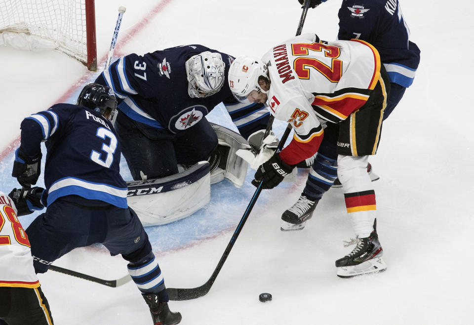 Calgary Flames' Sean Monahan (23) is stopped by Winnipeg Jets goalie Connor Hellebuyck (37) during the second period of an NHL qualifying round game, in Edmonton, Alberta, Thursday, Aug. 6, 2020. (Jason Franson=/The Canadian Press via AP)