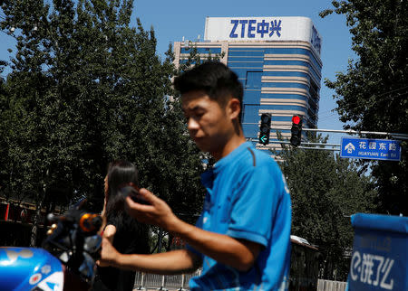 A delivery man uses a phone near a building of China's ZTE Corp in Beijing, China, August 29, 2018. REUTERS/Thomas Peter