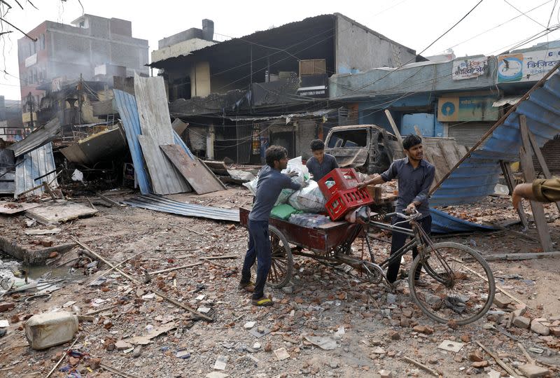 Shopkeepers carry their belongings in a rickshaw after salvaging them from their damaged shops in a riot affected area after clashes erupted between people demonstrating for and against a new citizenship law in New Delhi