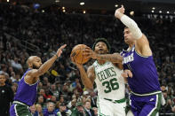 Boston Celtics' Marcus Smart (36) drives to the basket between Milwaukee Bucks' Jevon Carter, left, and Brook Lopez, right, during the first half of an NBA basketball game Thursday, March 30, 2023, in Milwaukee. (AP Photo/Aaron Gash)