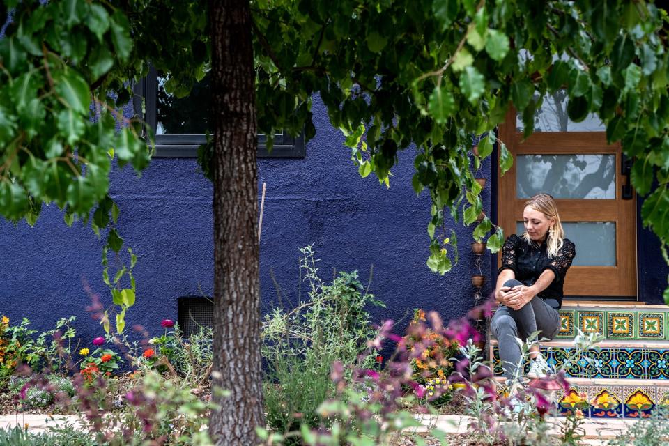 A woman sits on her porch, surrounded by wildflowers