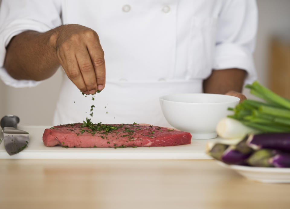 hand seasoning a raw slab of meat